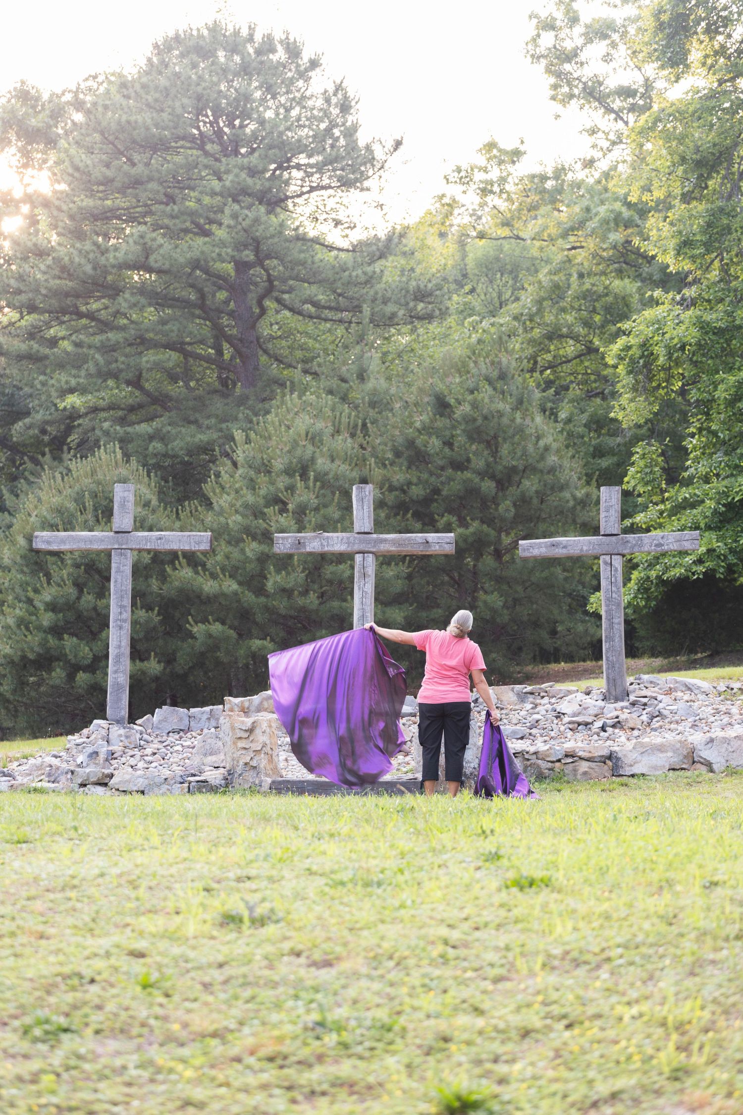 Woman waving purple fabric near three wooden crosses at Laurel Mountain Ministries.