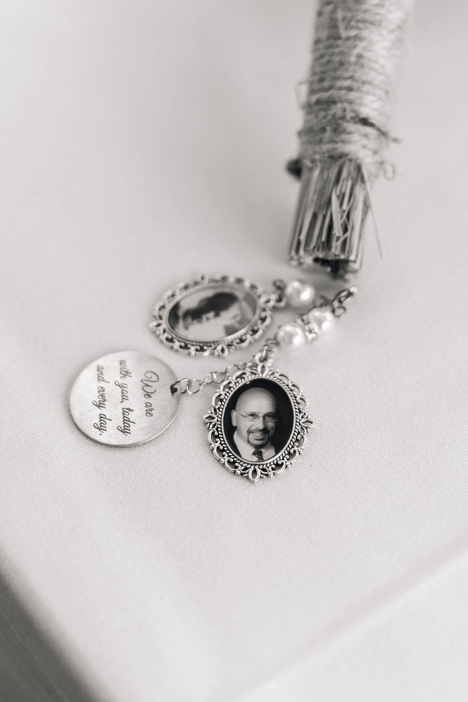 Black and white photo of wedding bouquet charm with memorial photo pendants and engraved keepsake disc.