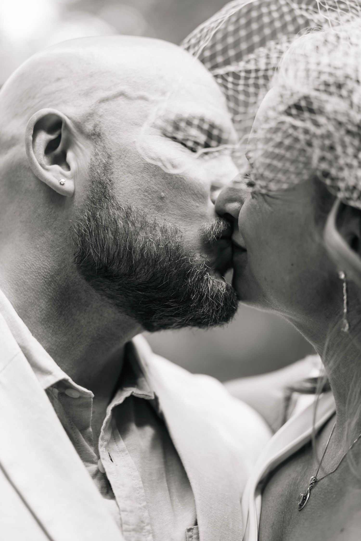 Black and white close-up of a bearded groom kissing his bride wearing a elegant birdcage veil in Philadelphia, PA.