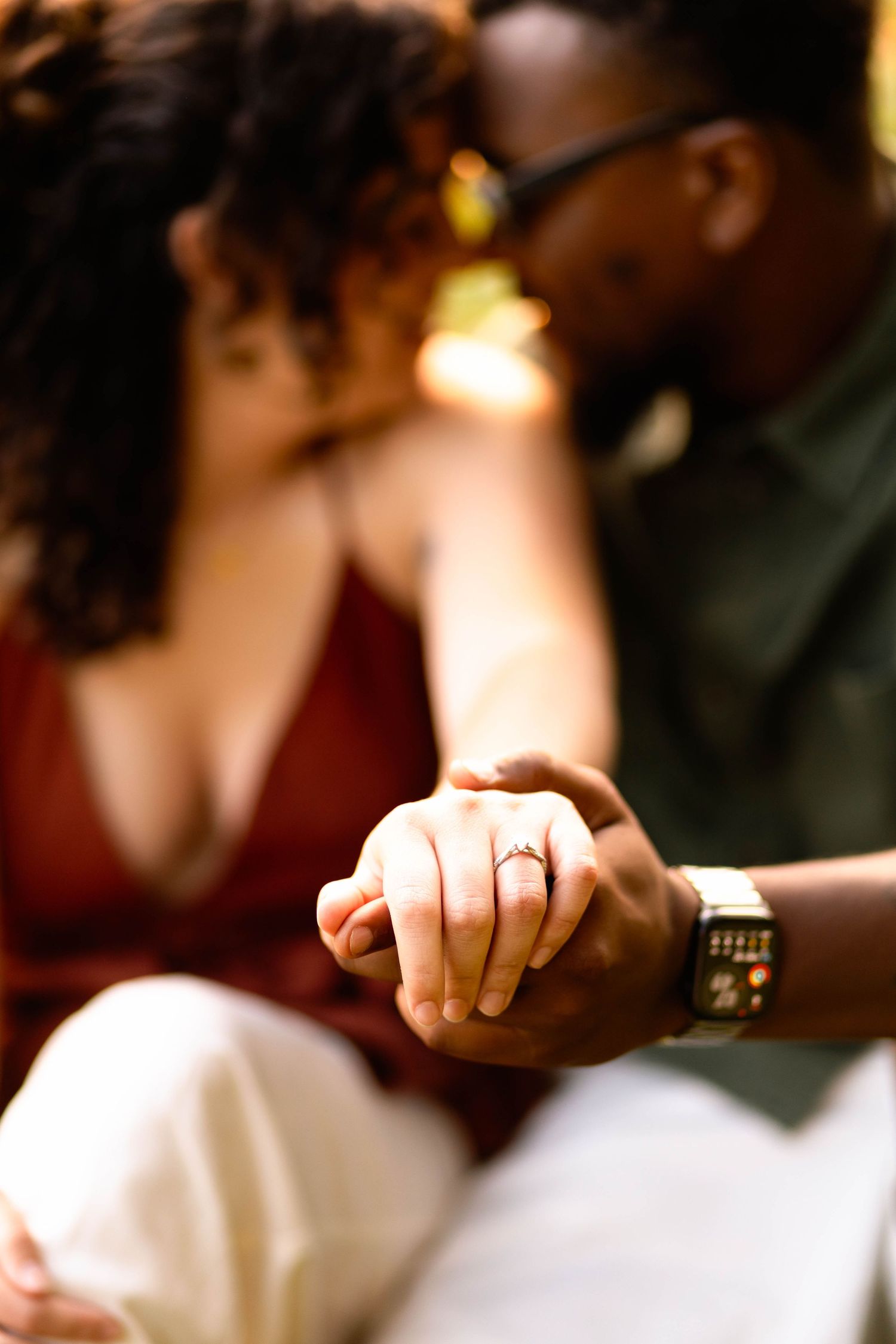 An engaged couple holds hands closely, showcasing a diamond engagement ring at Grings Mill in Reading, PA.