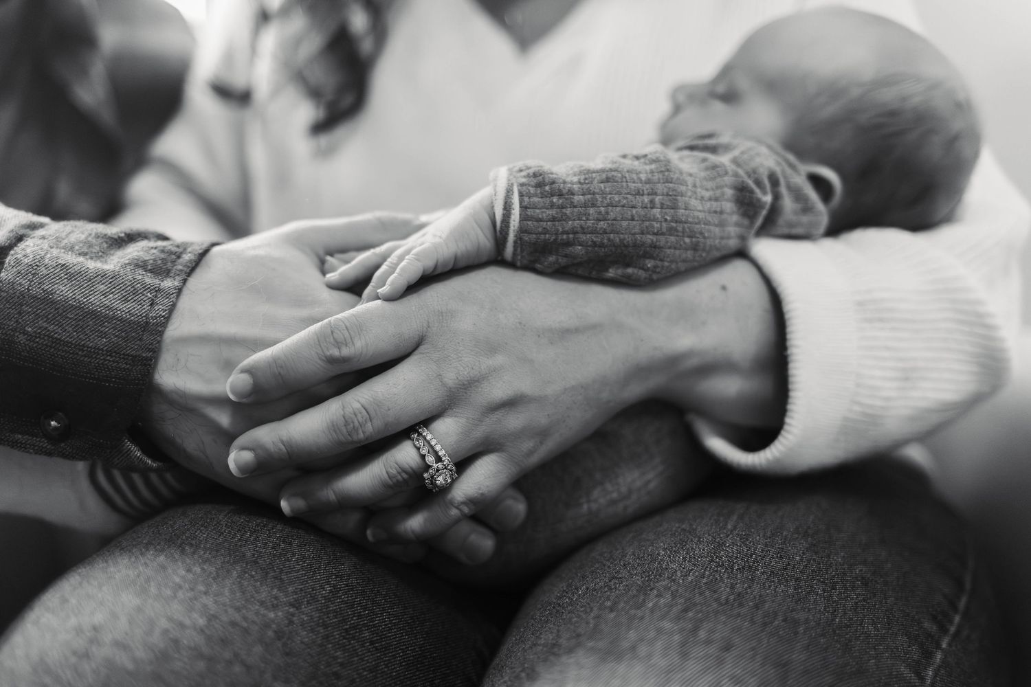 Black and white close-up of parents hands cradling their sleeping newborn baby during an at home newborn session in Pottstown, PA.