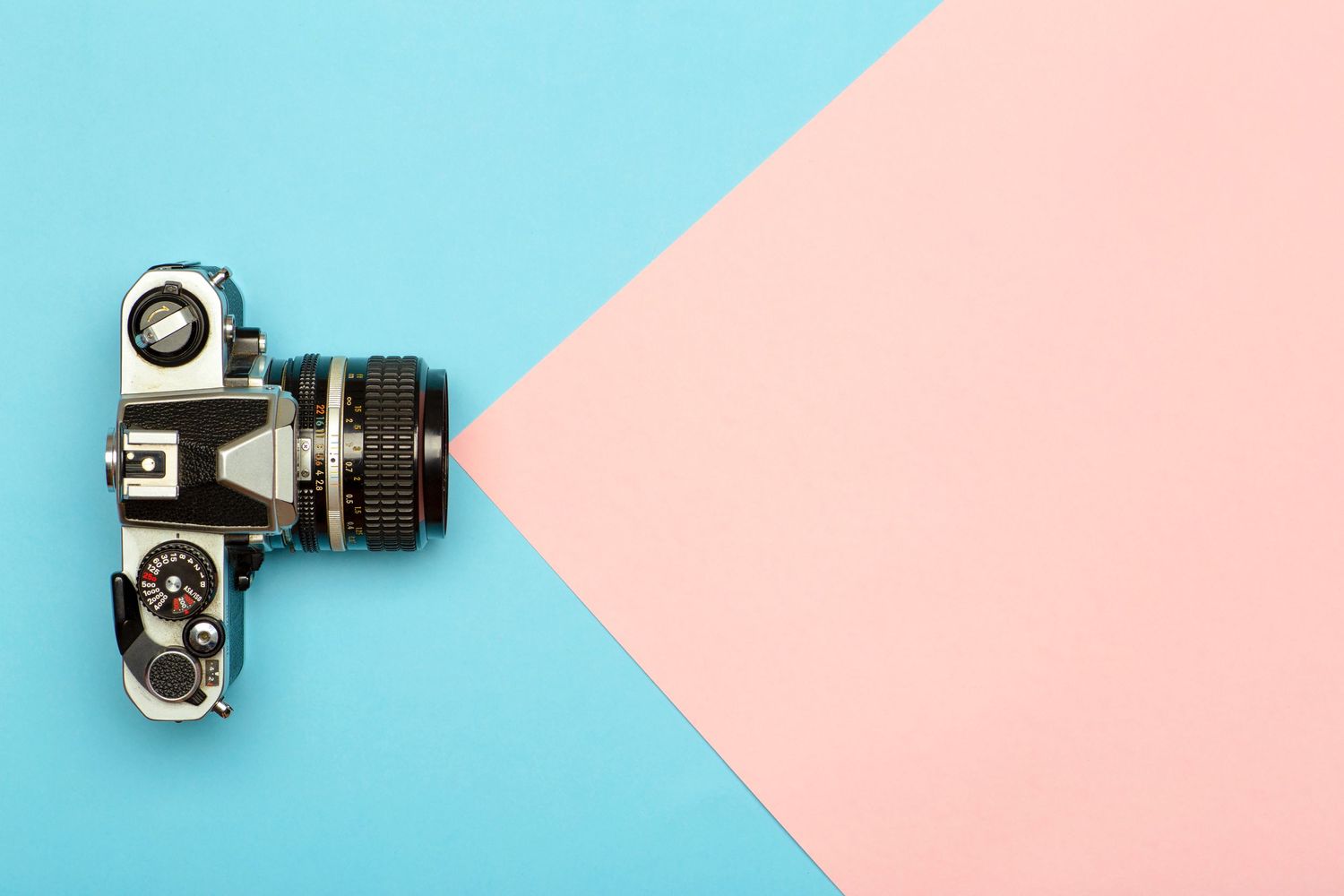 Vintage film camera on a minimalist blue and pink geometric background.