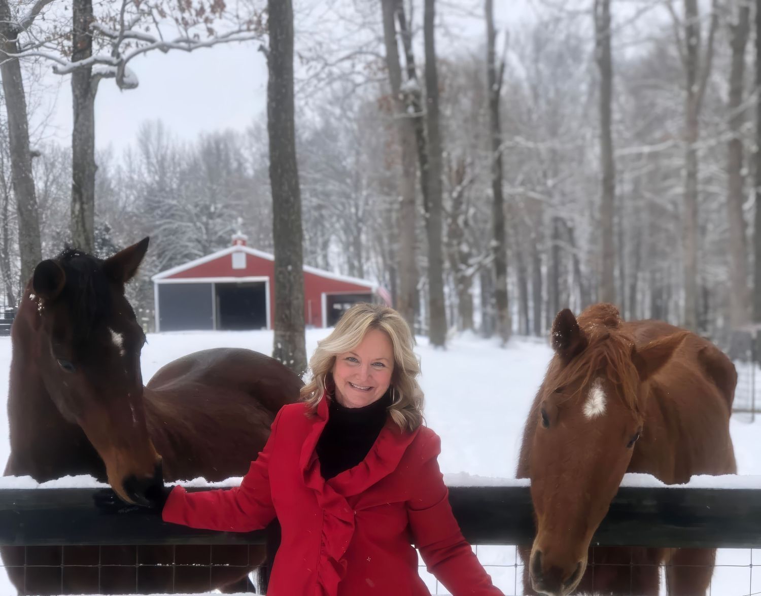 Photo of a woman with her two horses with a red barn in the snow in the background at Foell's Family Farm in Tennessee.