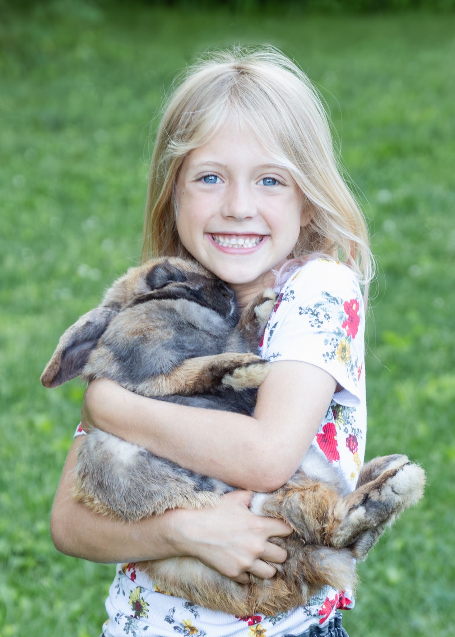 Photograph of a smiling girl chugging her pet rabbit.
