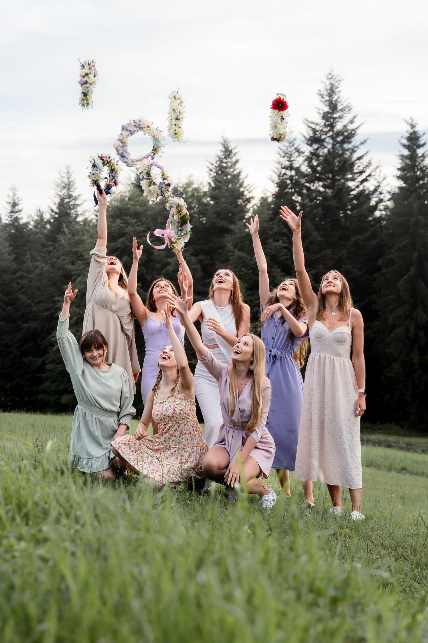 Przyjaciółki podrzucają wianki w boho stylu podczas wieczoru panieńskiego w Beskidach, Dobra, spontaniczna i radosna sesja zdjęciowa.