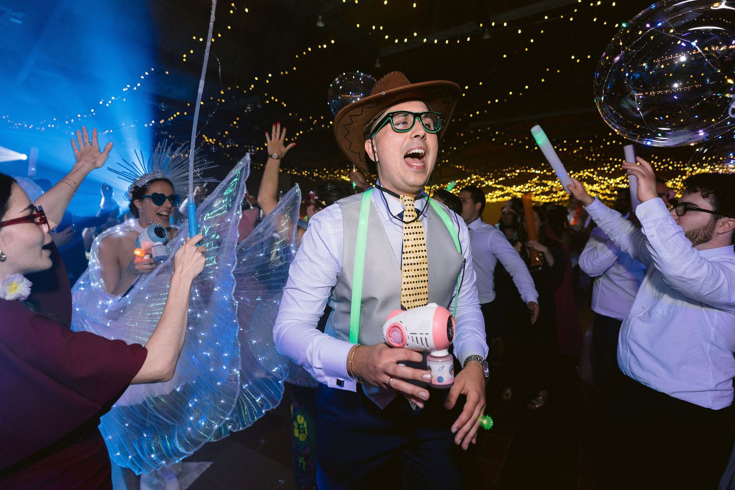 Wedding guests dance and celebrate with sparklers during a nighttime reception celebration.