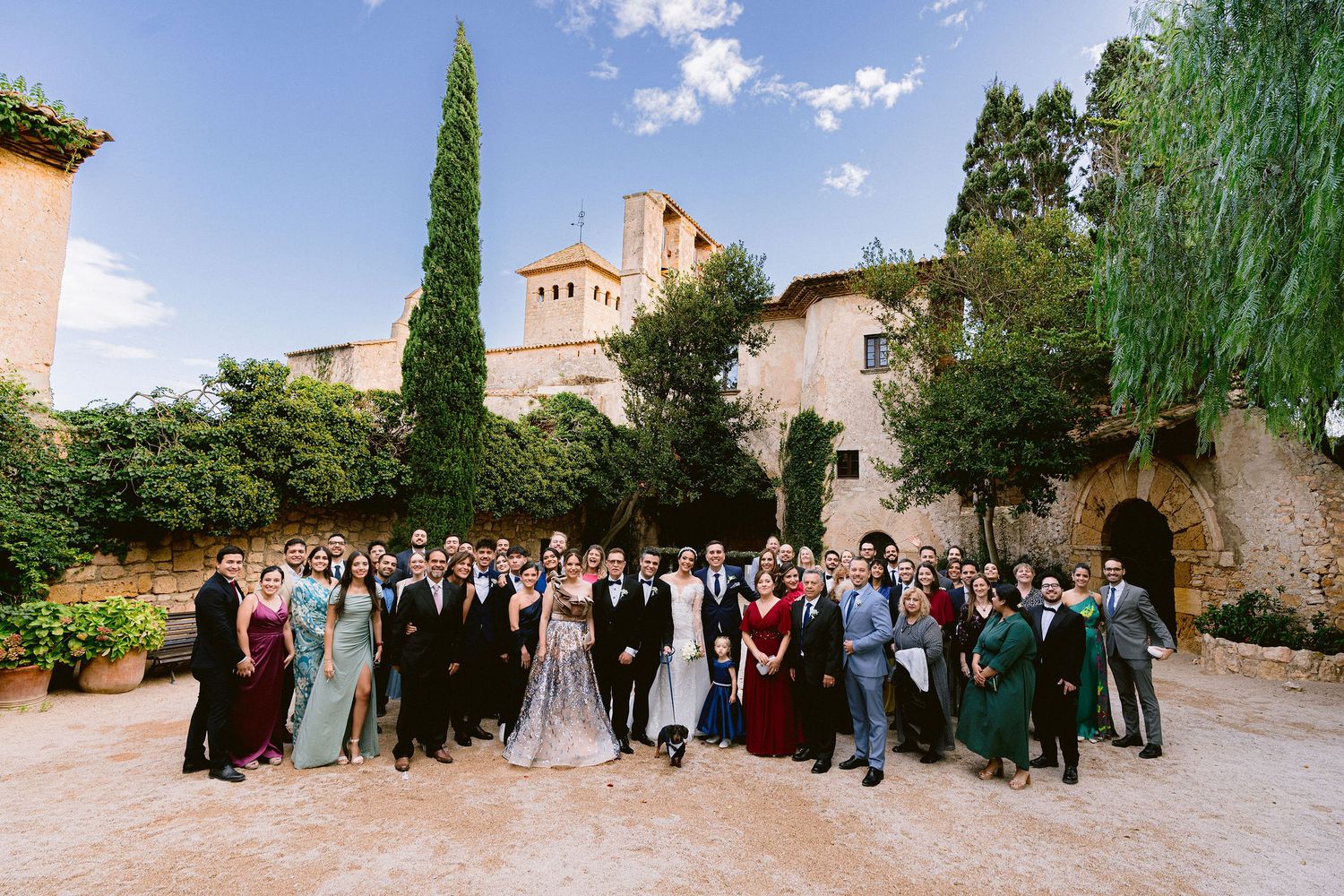 Wedding guests gather in a long panoramic sequence of photos showing an outdoor celebration at a historic venue.