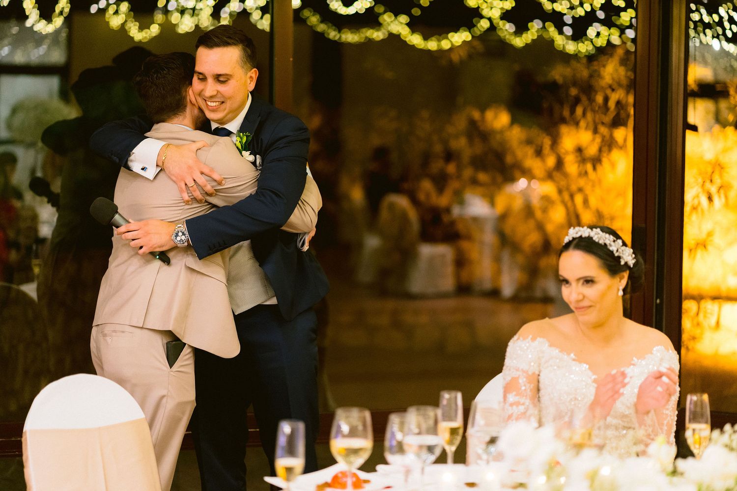 Warm evening lighting creates a romantic ambiance during a reception celebration with elegant table settings.