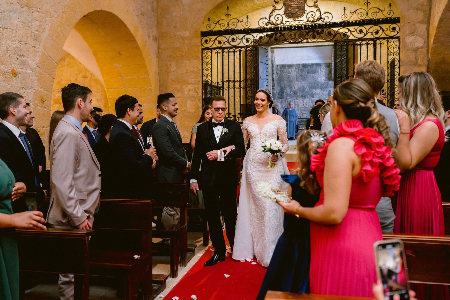 Wedding guests dancing and celebrating on the dance floor at an elegant stone-walled reception venue.