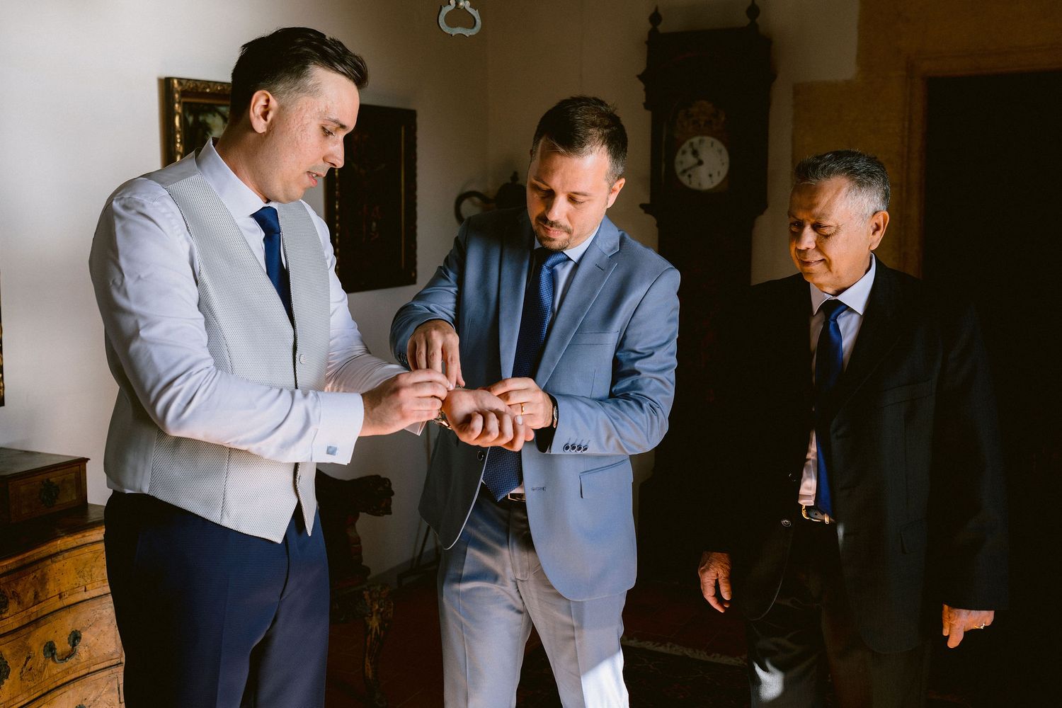 A group of men in formal business attire gather together for a conversation before an event.