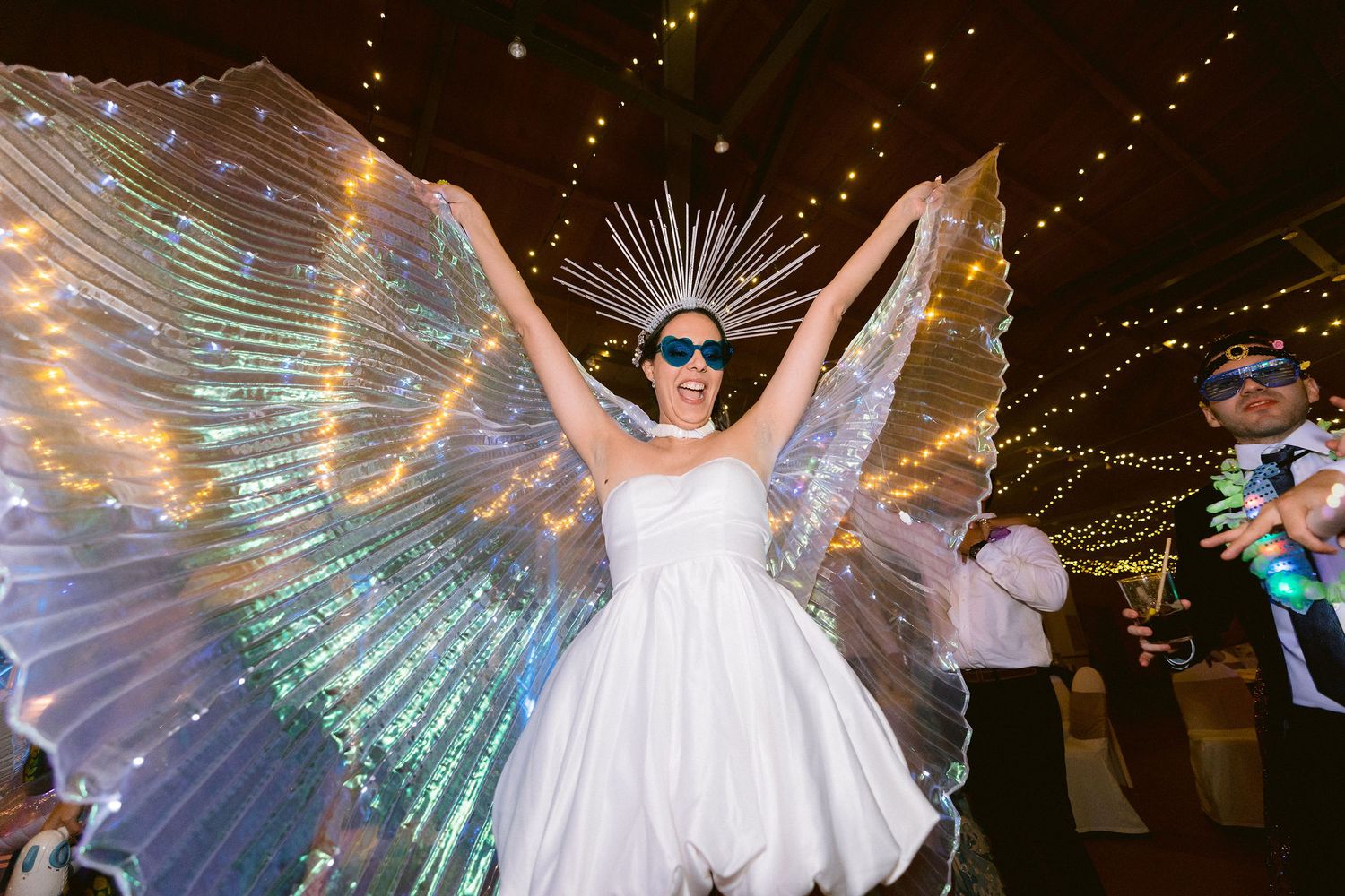 Wedding celebration with flowing white gowns and string lights creating a magical nighttime atmosphere.