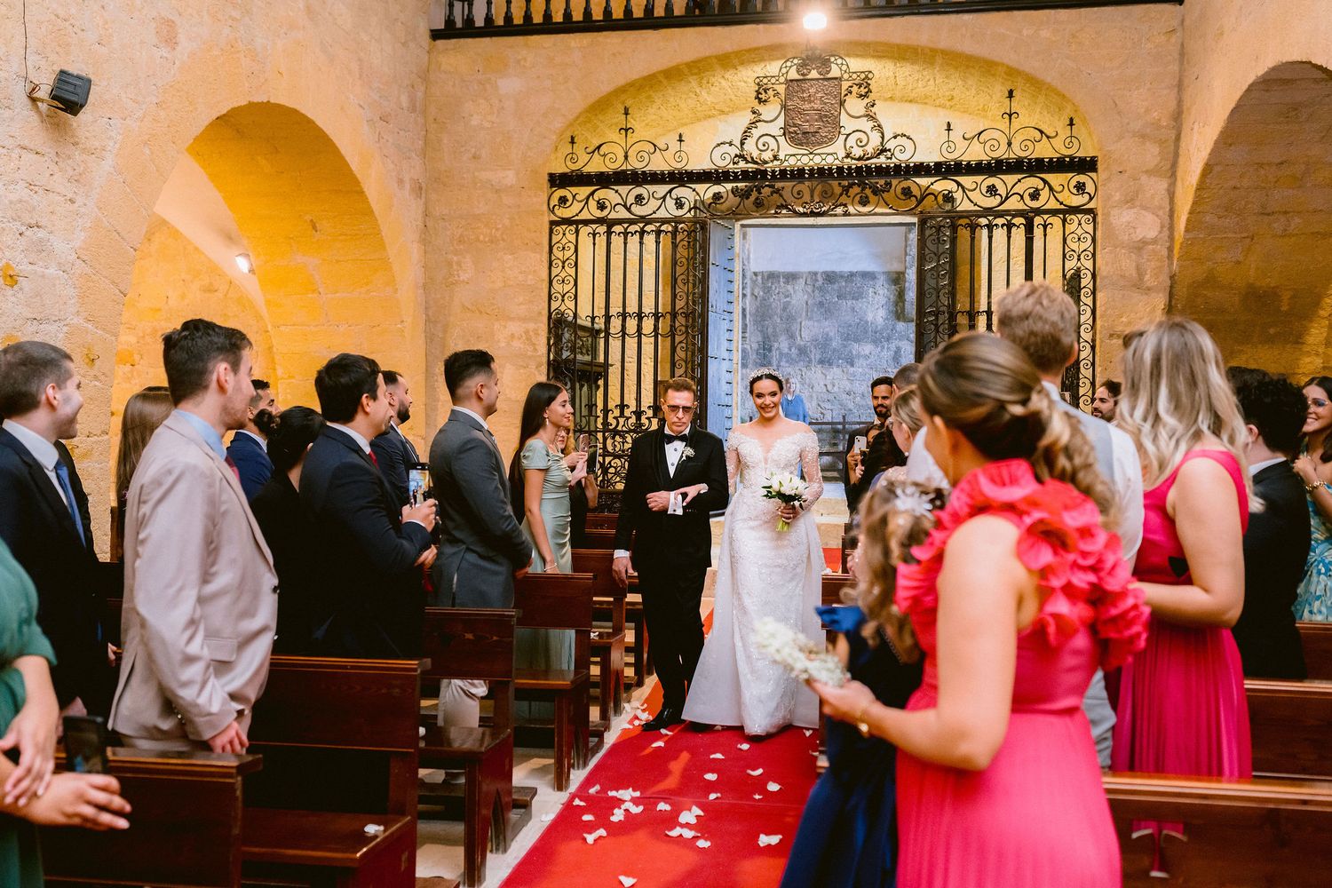 Wedding ceremony taking place inside a historic church with golden arches and ornate iron gates at the altar.