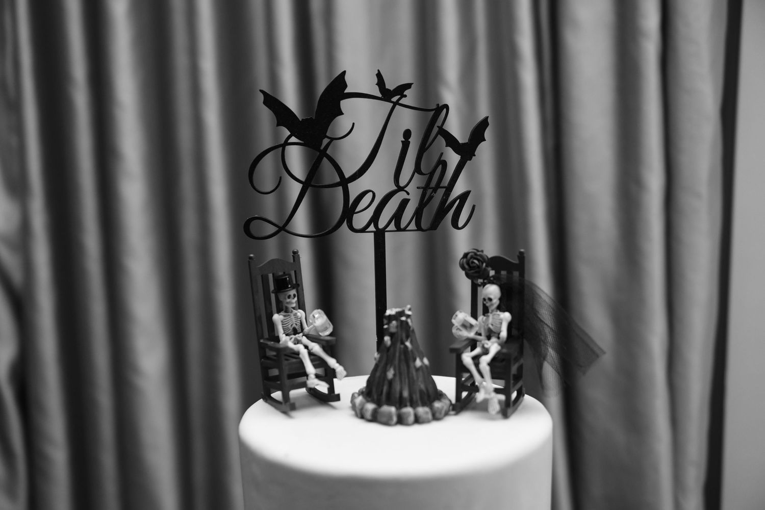 Decorative cake toppers silhouetted against a gray backdrop at a wedding reception.