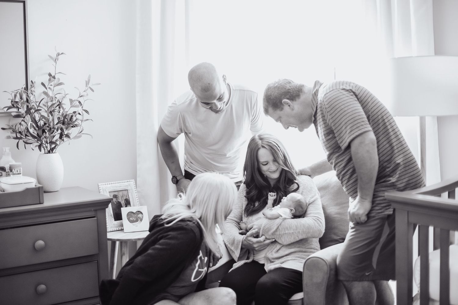 Family gathered around newborn baby during an intimate lifestyle photography session at home.