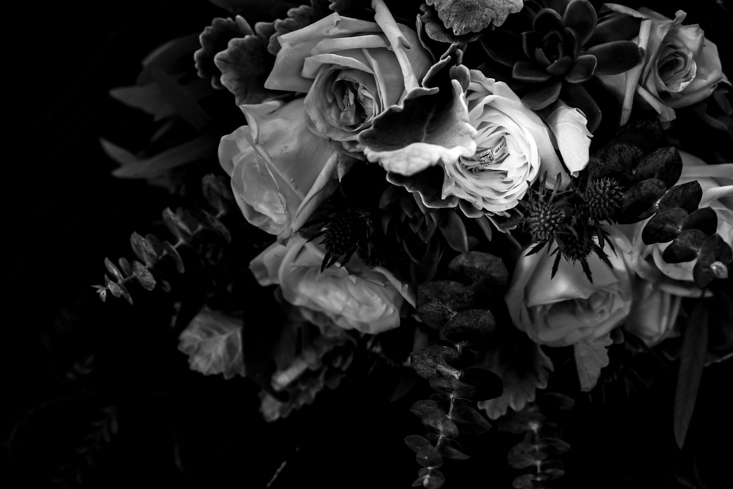 Black and white floral arrangement detail with roses against dark background.