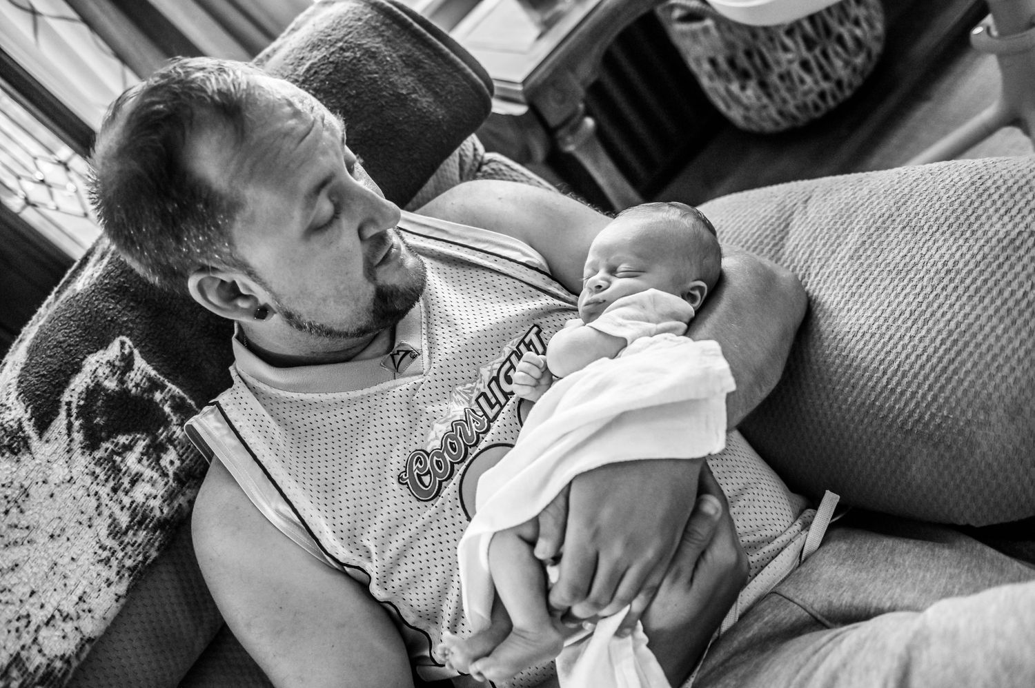 Black and white photo collage showing tender moments between a parent and newborn baby in various poses.