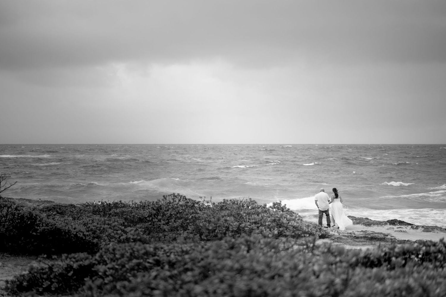 Black and white panoramic view of rocky coastal landscape with ocean waves.