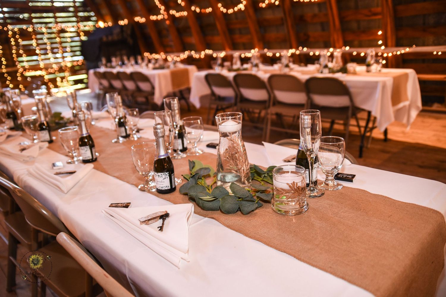 Rustic wedding reception table setup with string lights and simple table settings.