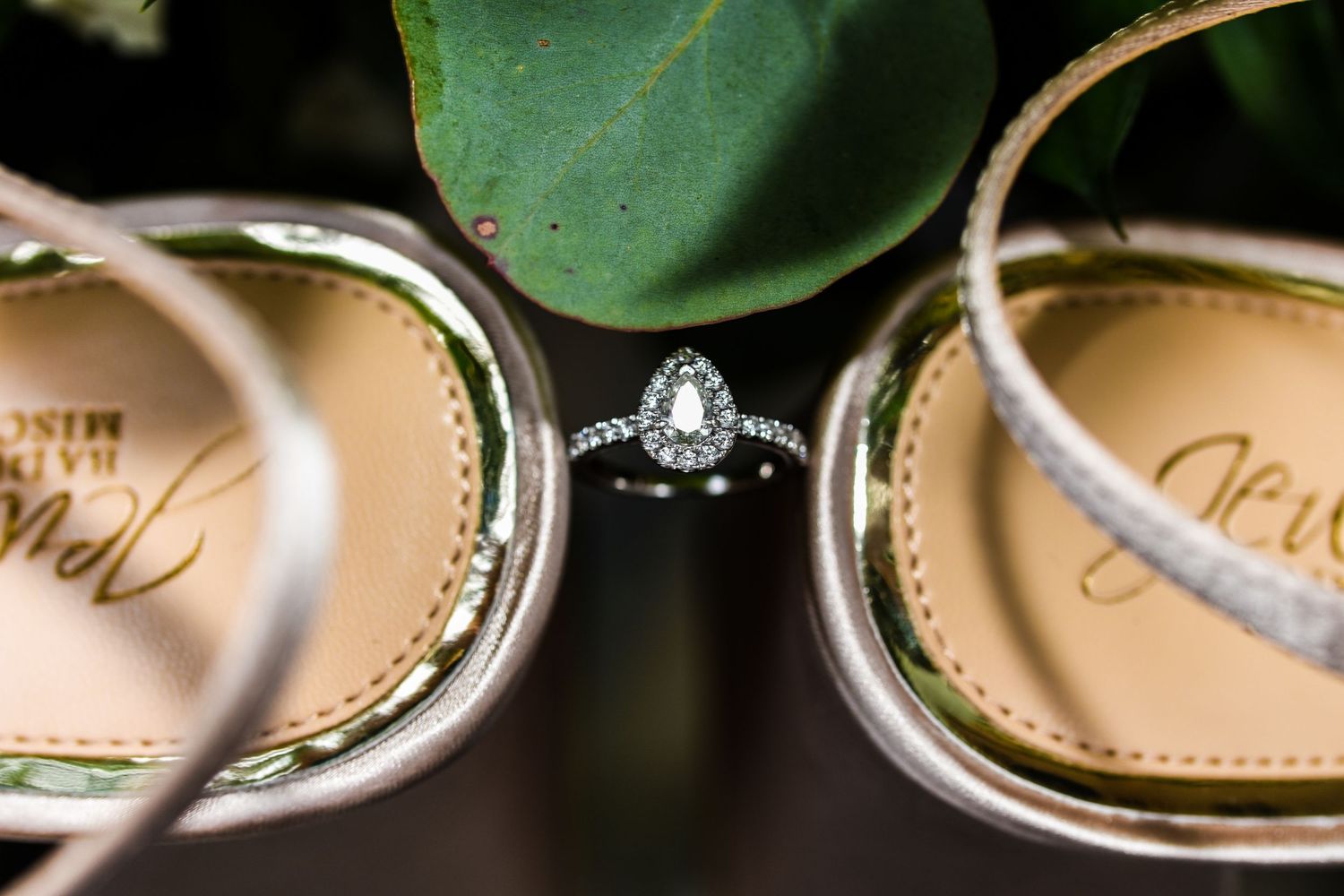 Diamond engagement ring artistically photographed between wedding shoes.