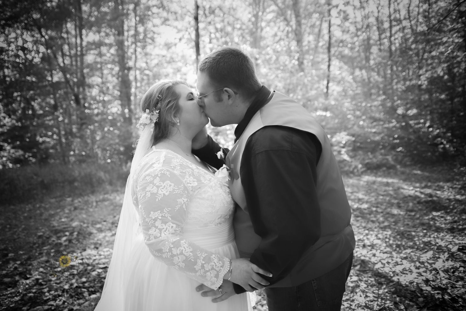 A romantic black and white forest portrait with sunlight filtering through trees.
