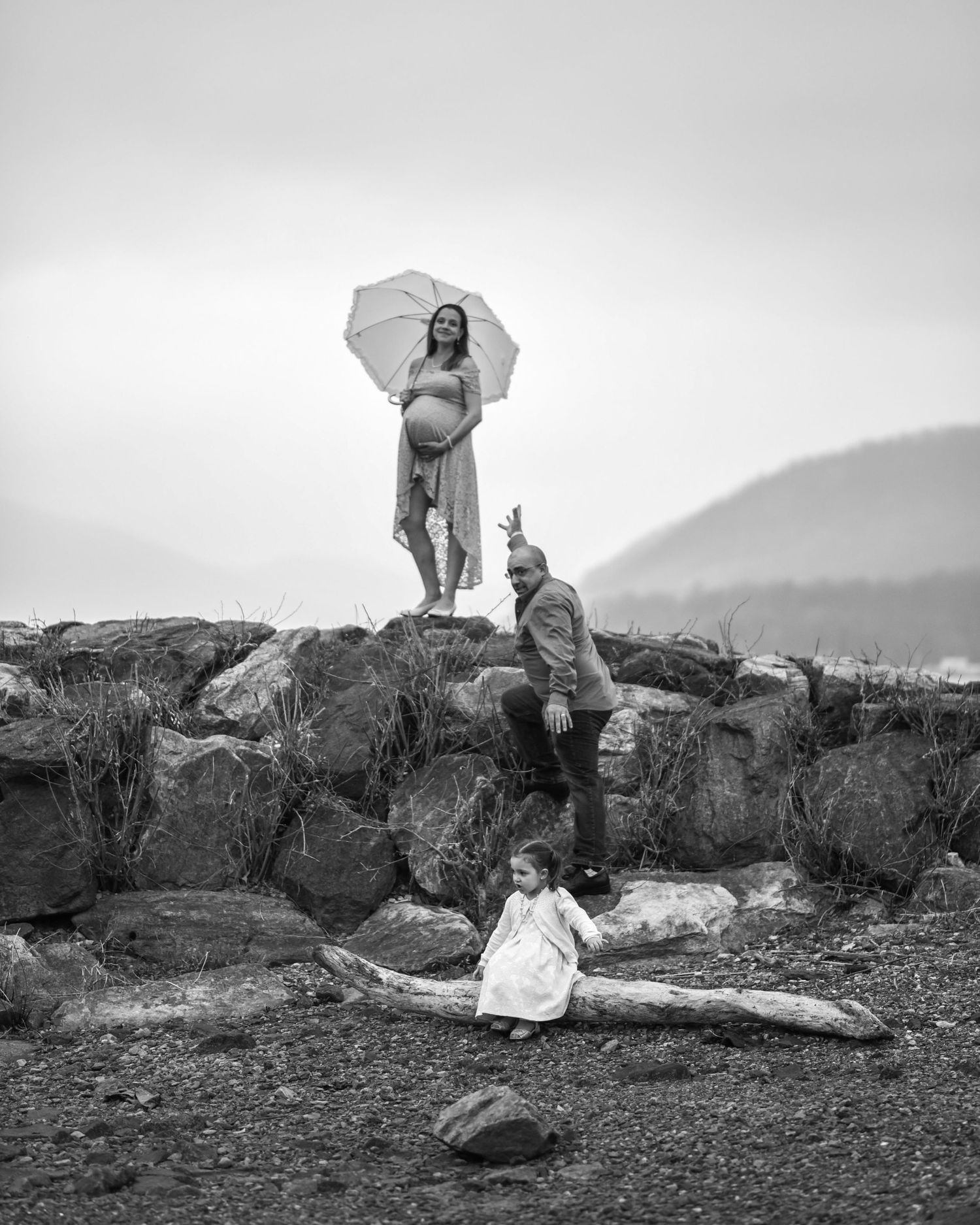 A series of black and white photographs showing people climbing and posing on large coastal rocks by the ocean.