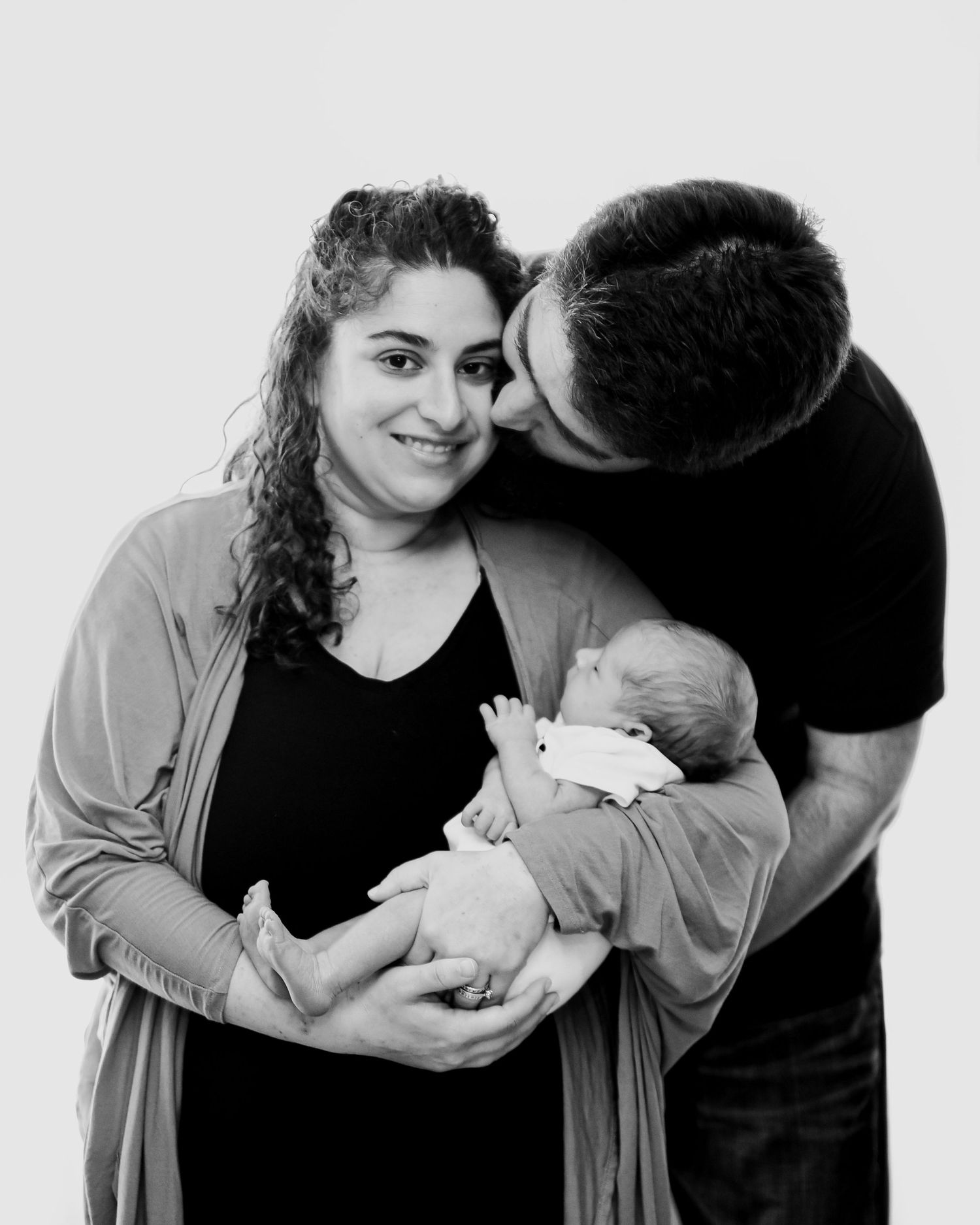A series of four black and white photos showing tender moments between parent and baby in intimate close-up portraits.