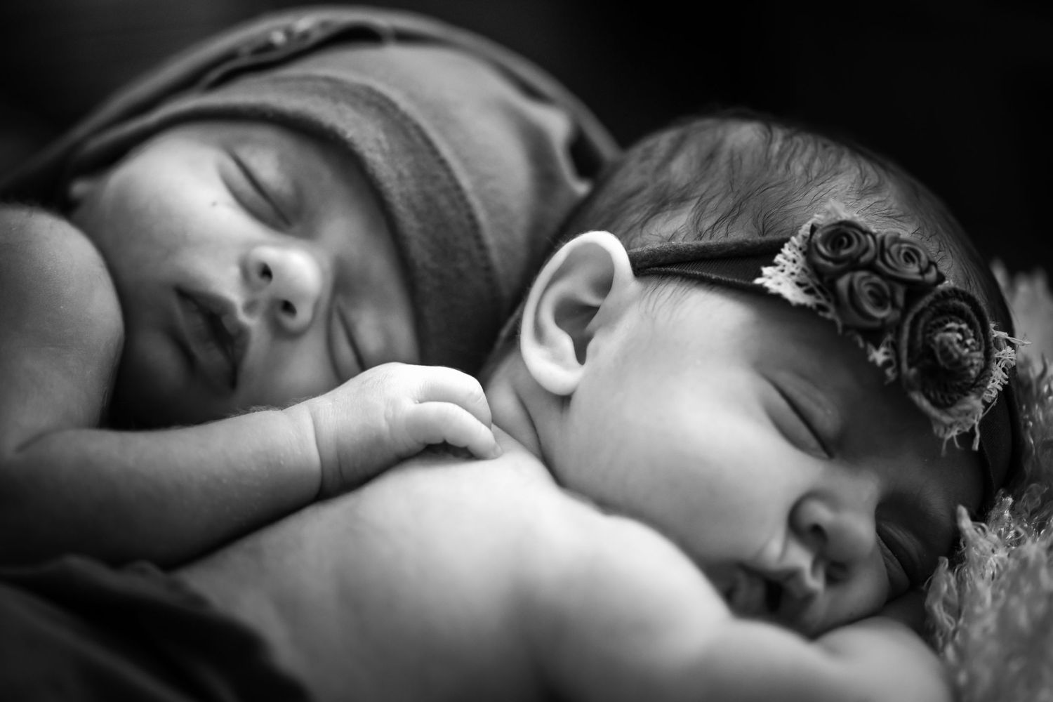A black and white close-up photograph of two sleeping babies peacefully resting together.