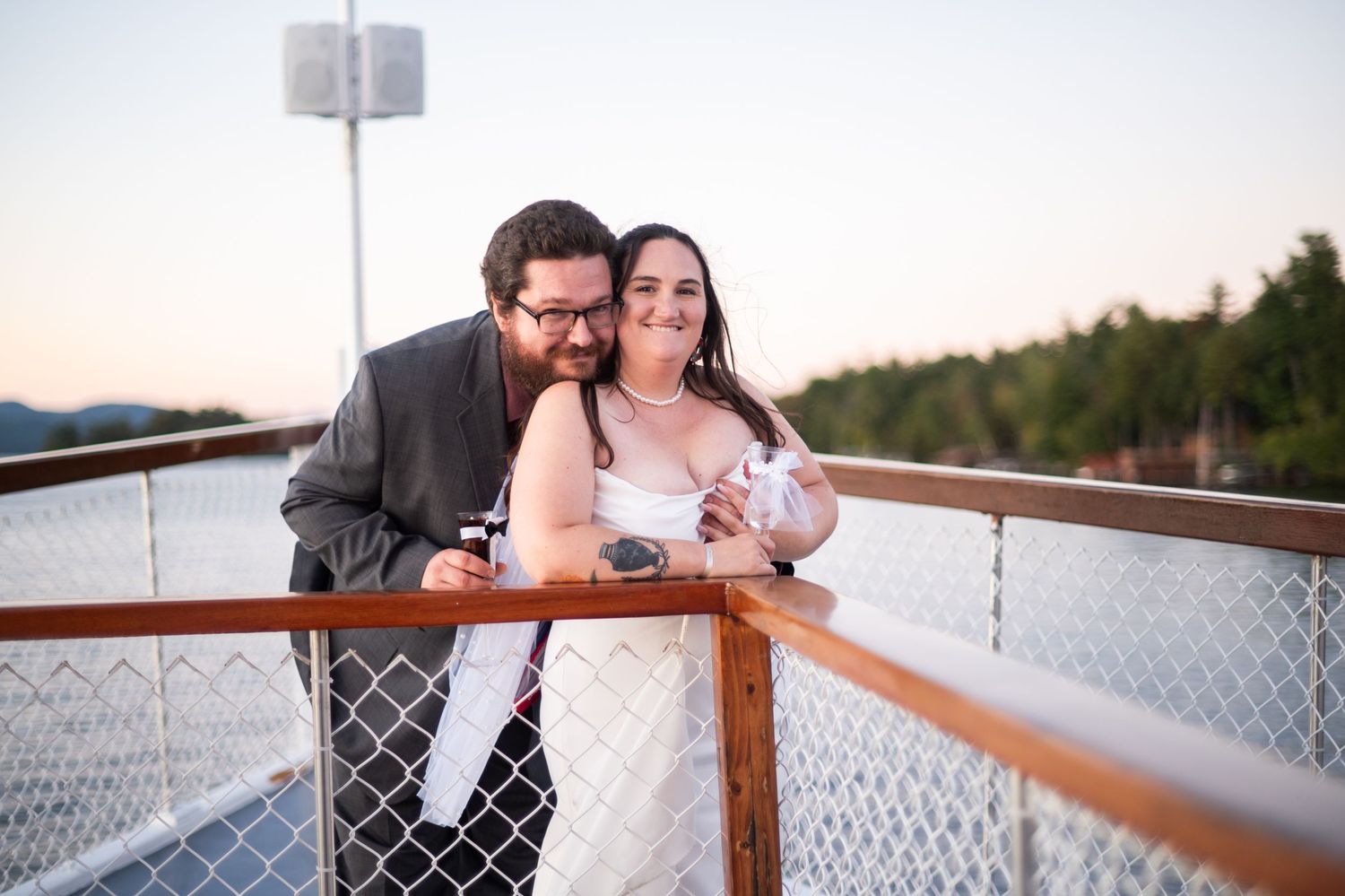 A couple shares a romantic moment on a boat deck during sunset.