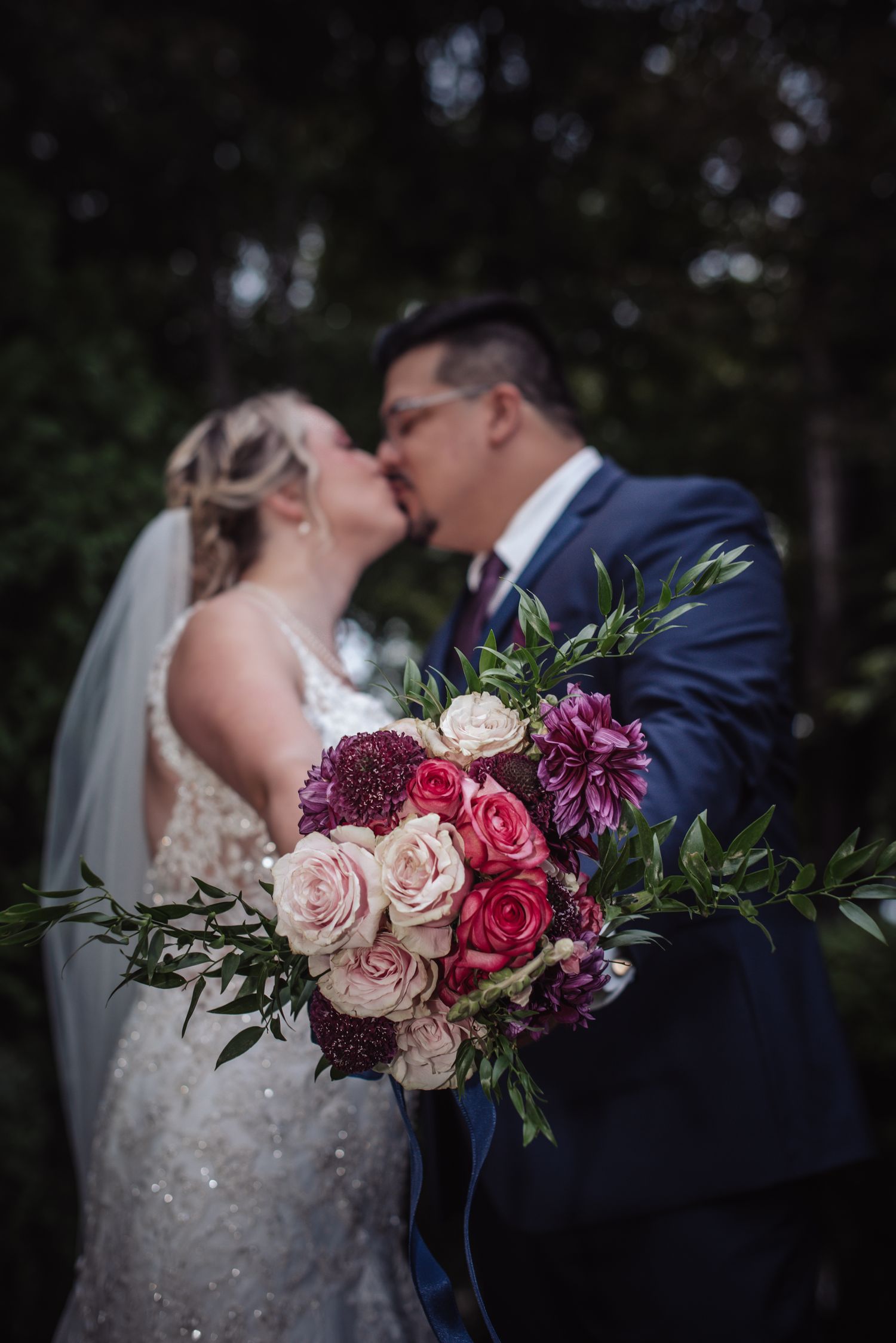 A romantic wedding portrait featuring a stunning bouquet with pink and burgundy flowers.