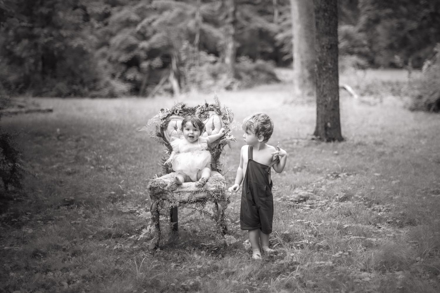 Children play together outdoors in a black and white photograph capturing candid moments.