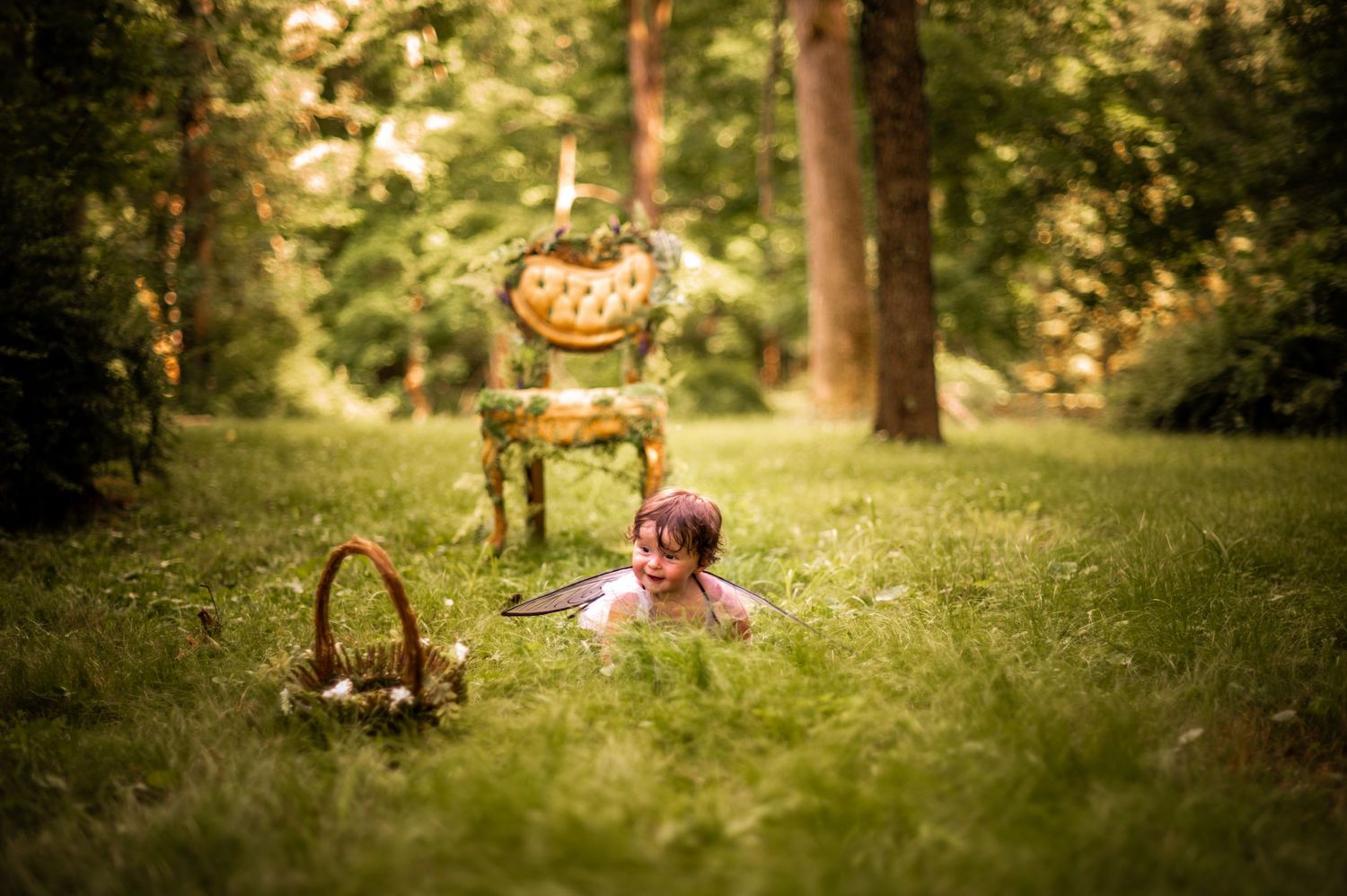 A vintage chair and basket set up for a whimsical outdoor photo session in a sunlit forest clearing.