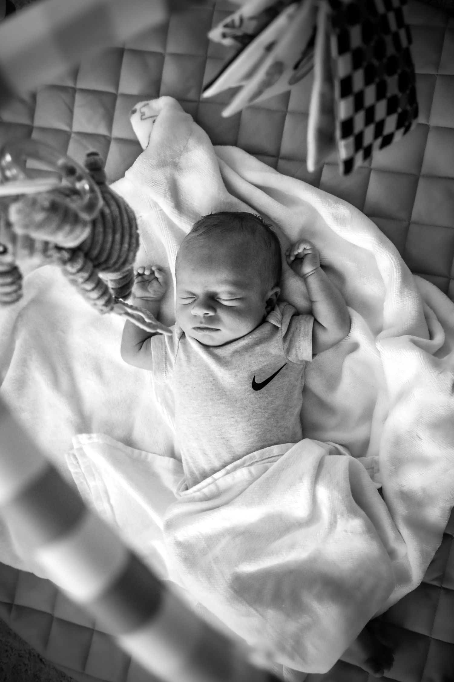 Black and white photo sequence showing a sleeping baby in white clothing on a checkered blanket.