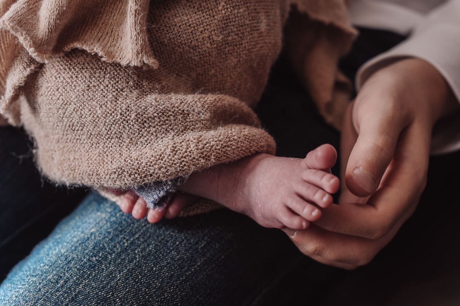 Close-up view of hands holding a warm knitted sweater showing cozy textile details and craftsmanship.