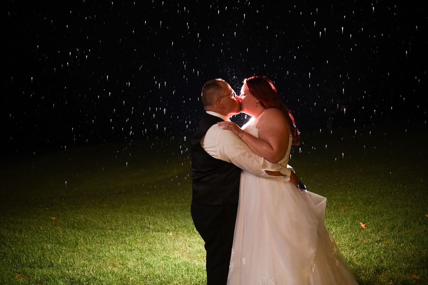 Nighttime wedding photo with rain falling against dark background.