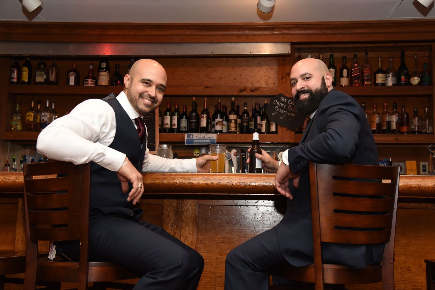 Wedding party relaxing at bar counter in formal attire.
