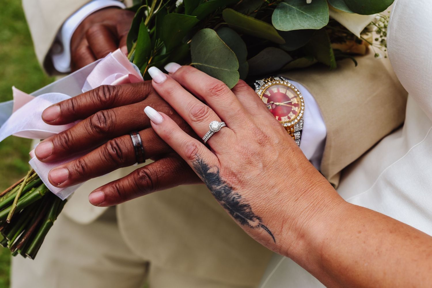 Close-up of hands exchanging wedding rings during an outdoor ceremony.