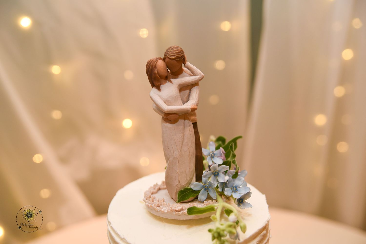 A delicate wedding cake topper with soft bokeh lights in the background.