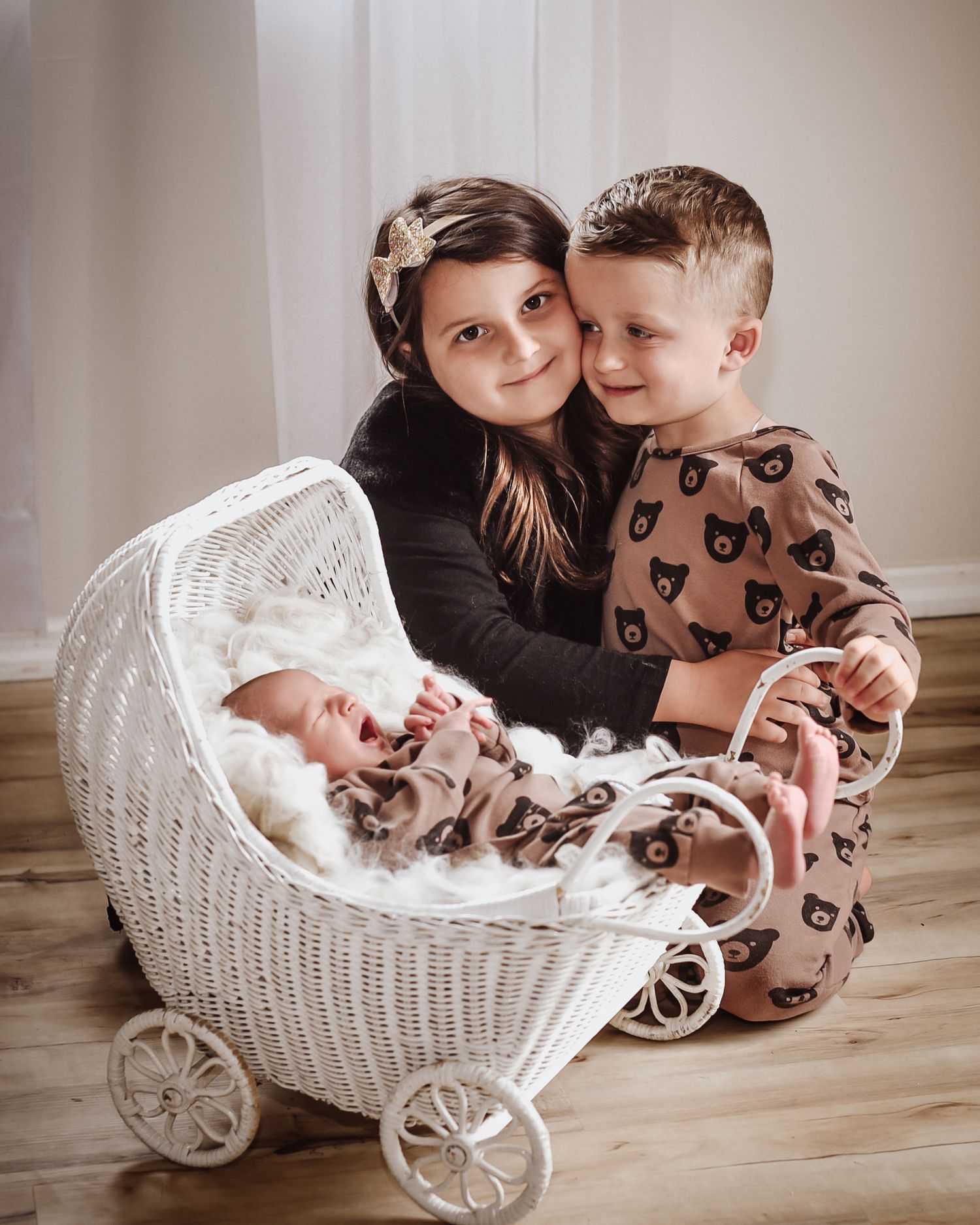 A series of photos showing children looking into a white wicker baby carriage on a wooden floor.