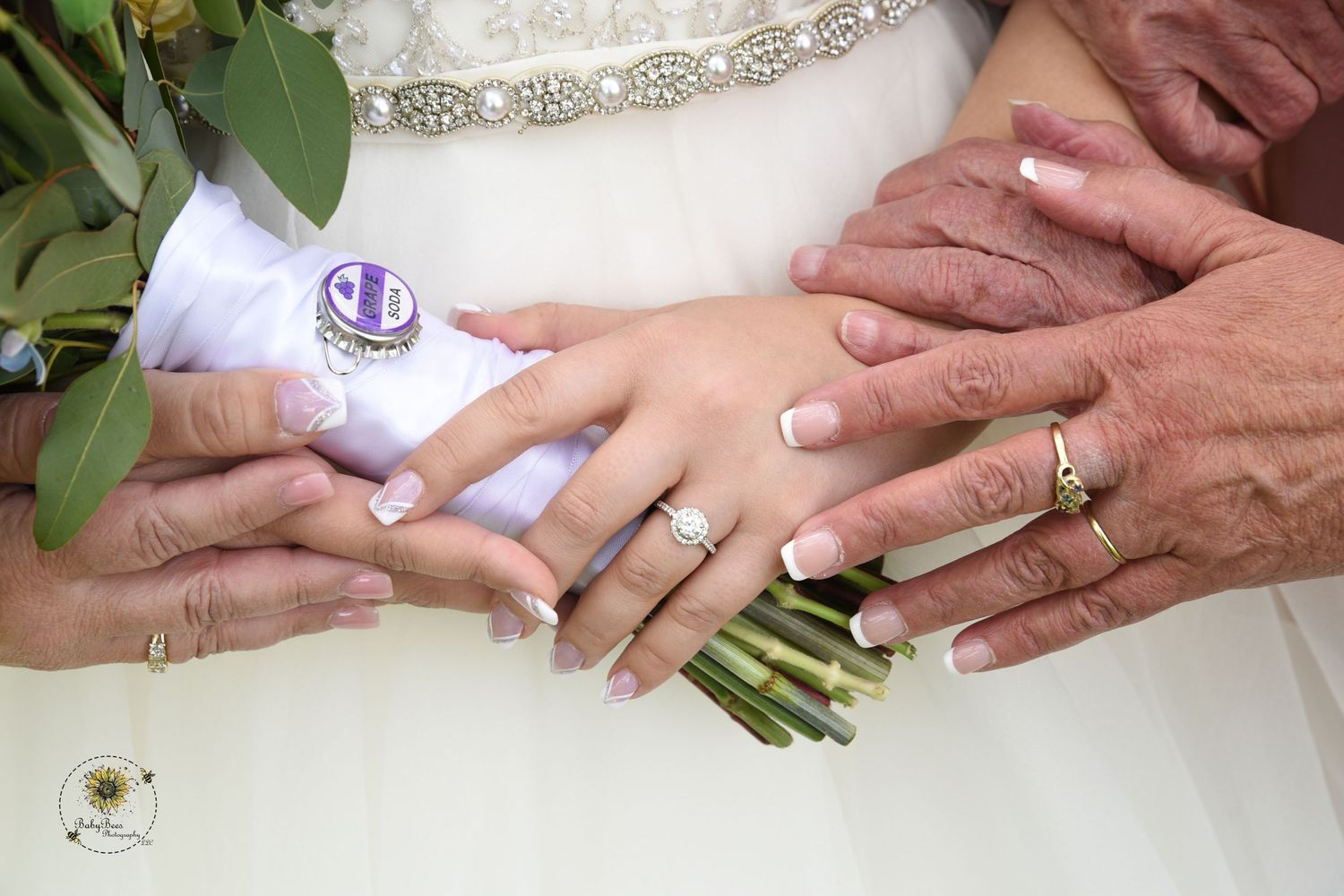 Close-up of wedding rings and hands holding a floral bouquet with white flowers.