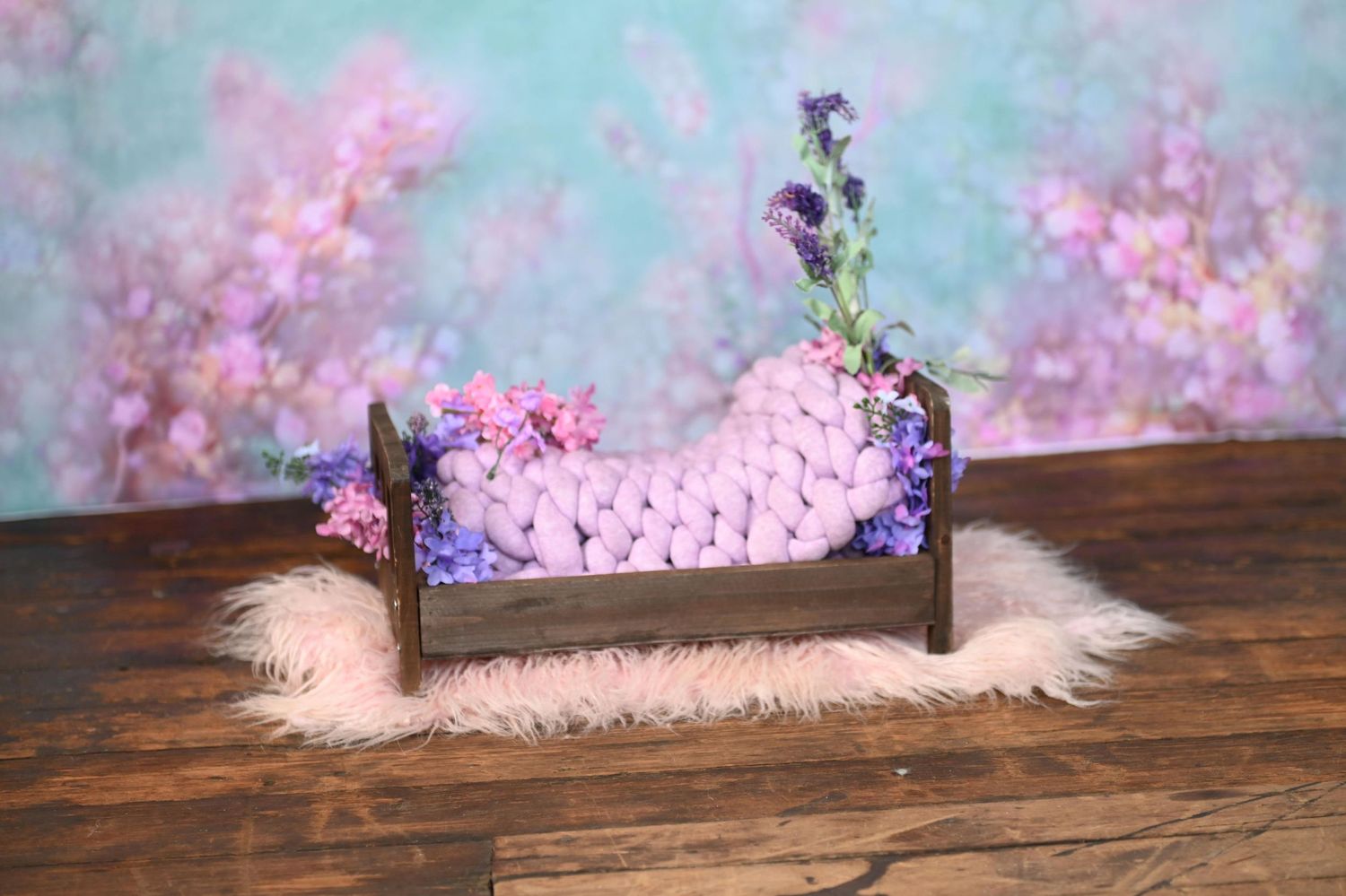 A rustic wooden backdrop with pink cherry blossoms and dreamy blue lighting creates a romantic photography setting.