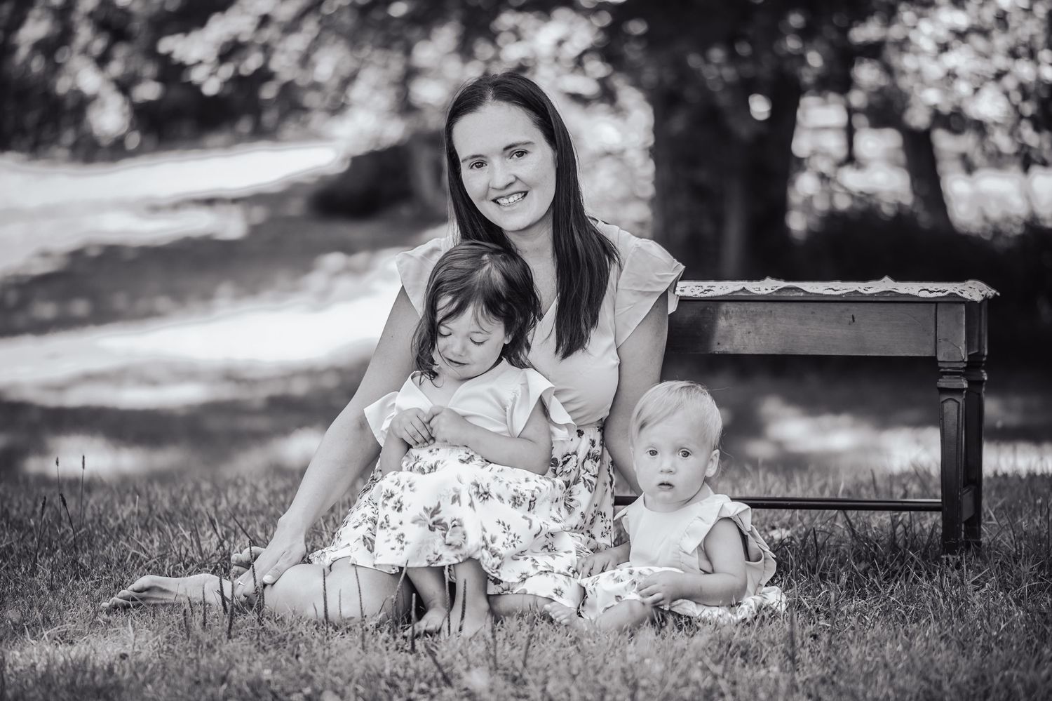 A family relaxes together on grass during an outdoor black and white photography session.