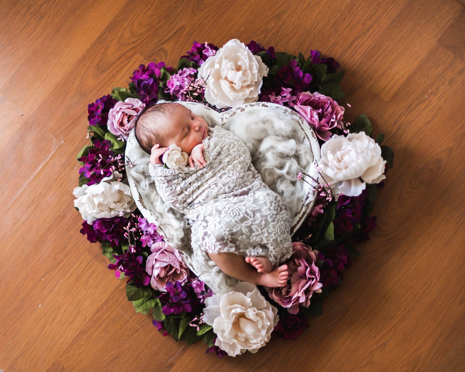 Delicate white and purple floral arrangement laid on a polished wooden surface creates an elegant display.