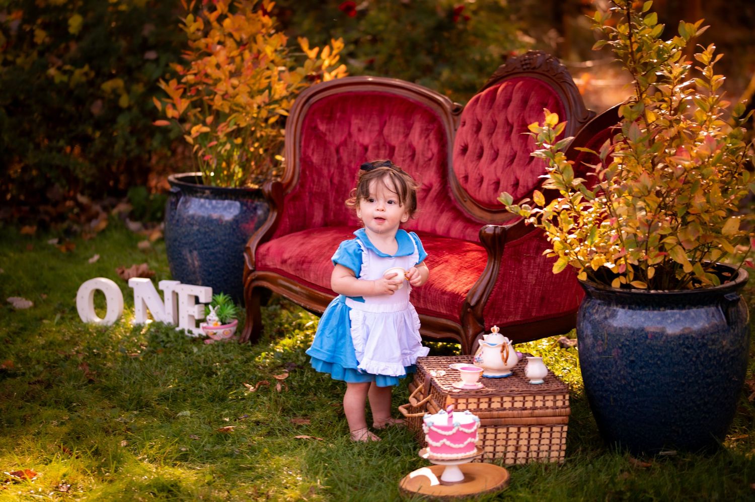 Children play and pose in a vibrant autumn garden setting with golden leaves and red furniture accents.
