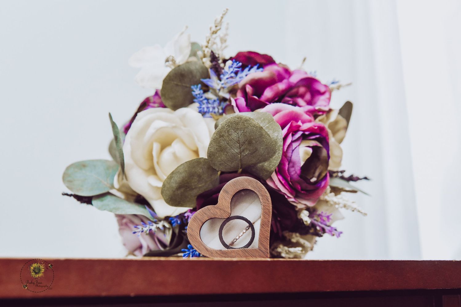 Wedding rings nestled among pink and purple flowers with greenery accents.