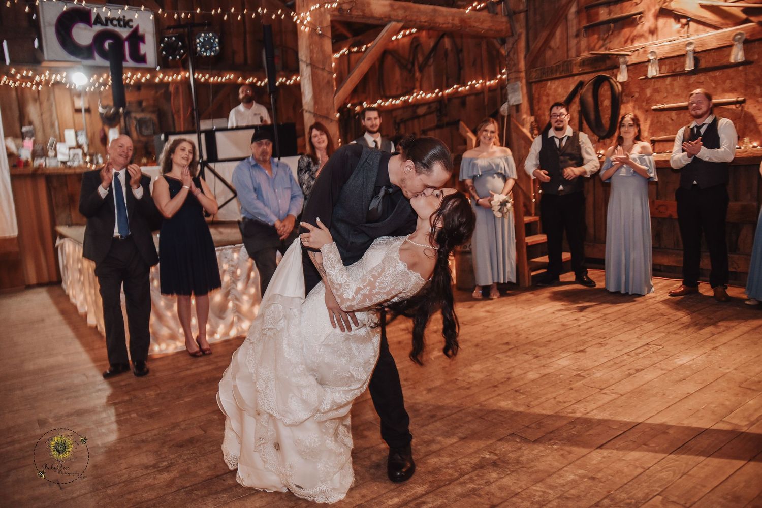 Wedding reception dance floor scene with string lights and rustic barn wood interior.