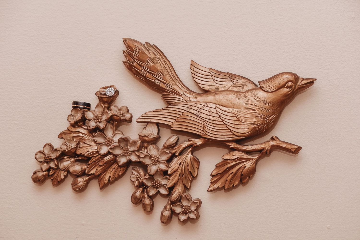 Decorative copper-toned metal wall art featuring a bird perched on flowering branch.