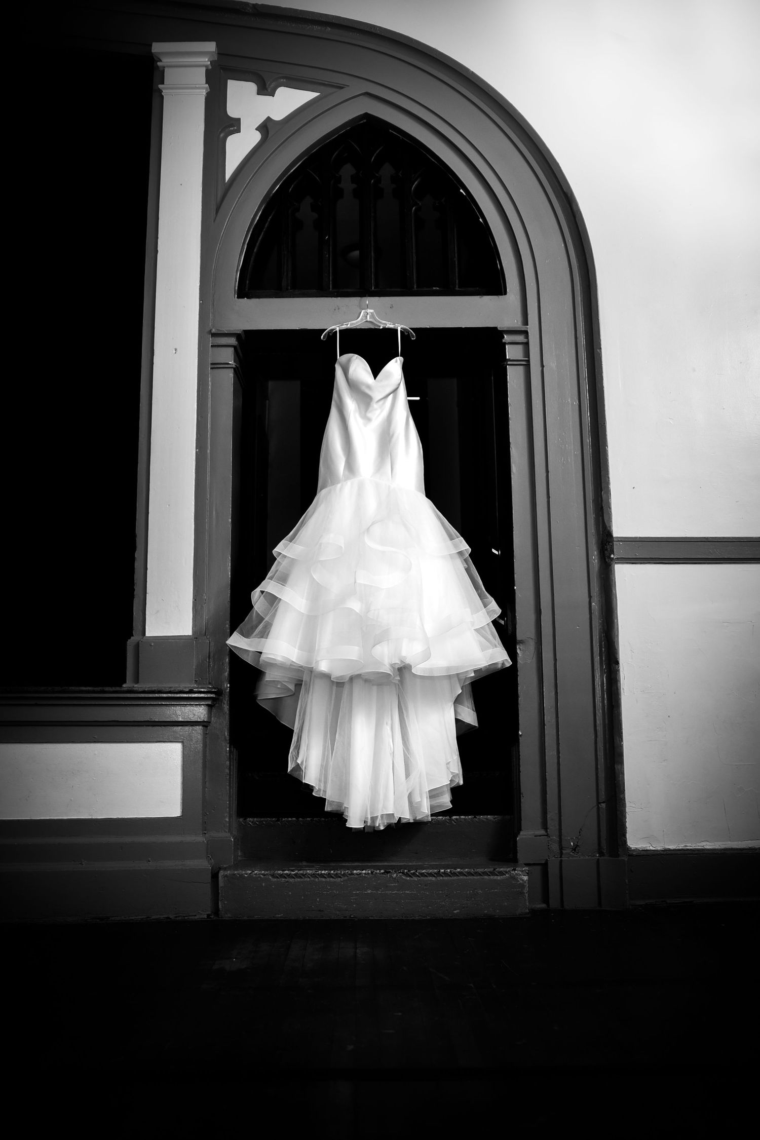 Dramatic black and white photos of a white wedding dress displayed in an arched alcove.
