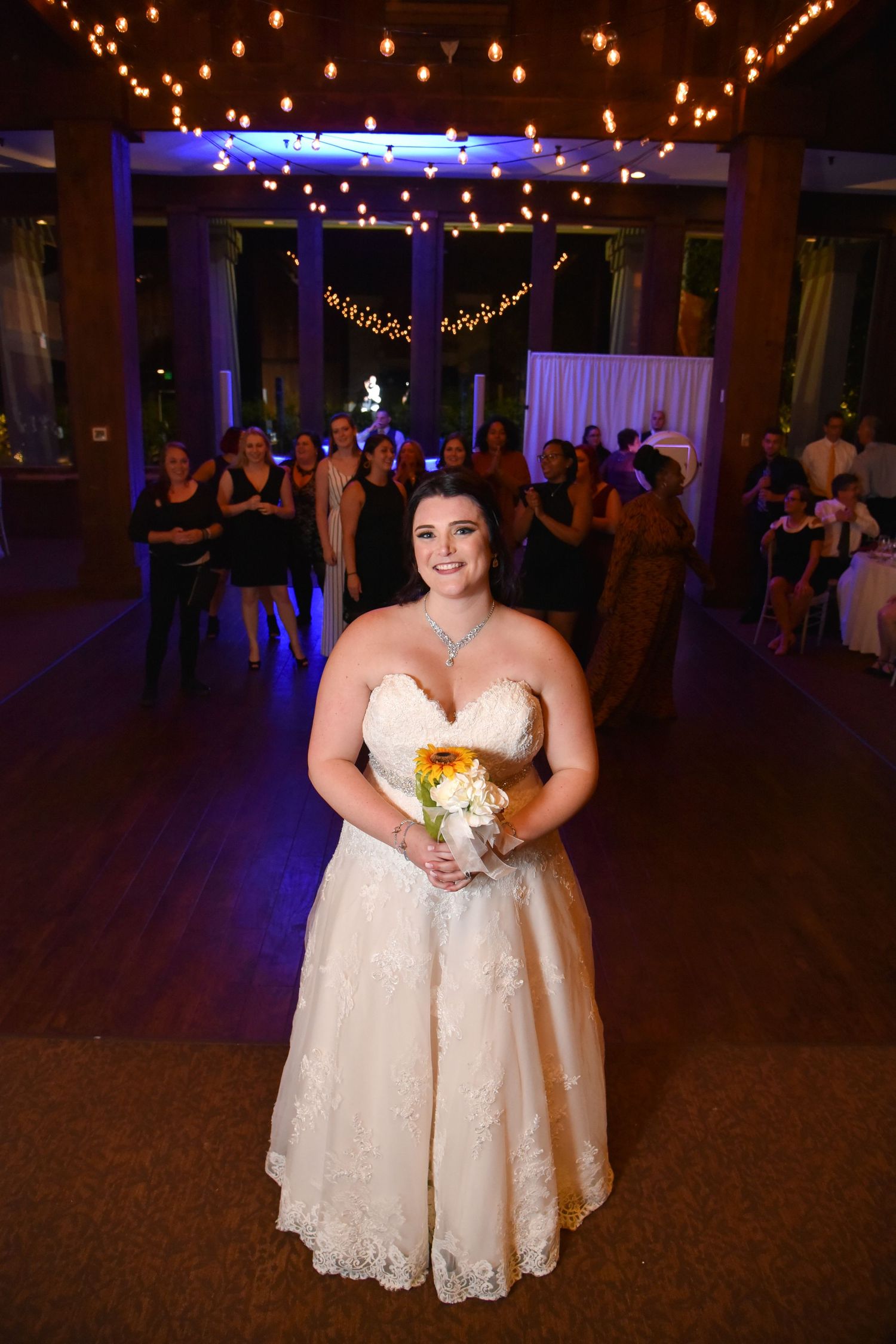 Wedding reception dance floor with string lights and blue uplighting creating a festive atmosphere.