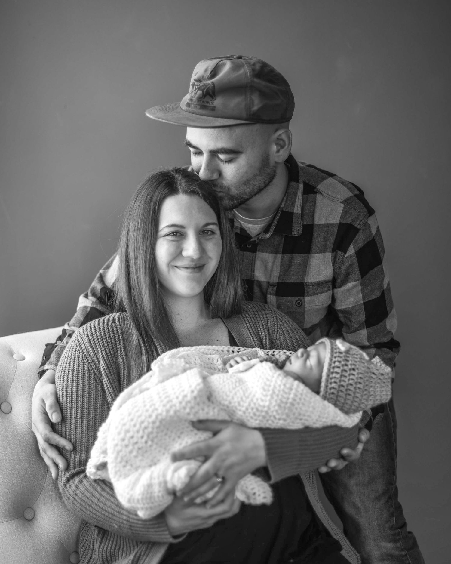 A black and white photo series showing a couple holding and admiring their newborn baby in tender moments.