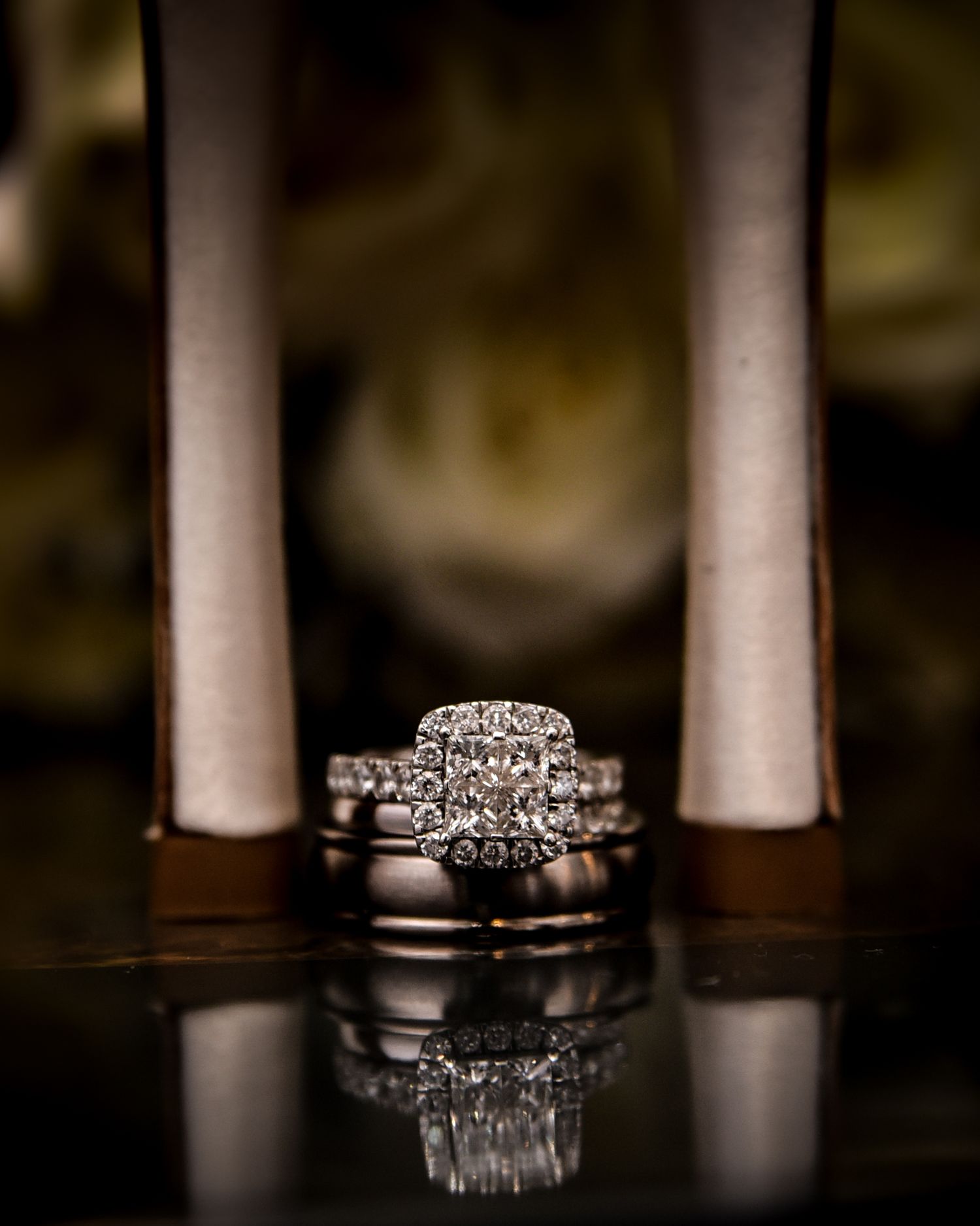 Diamond wedding ring set photographed with dramatic lighting and reflection on dark surface.